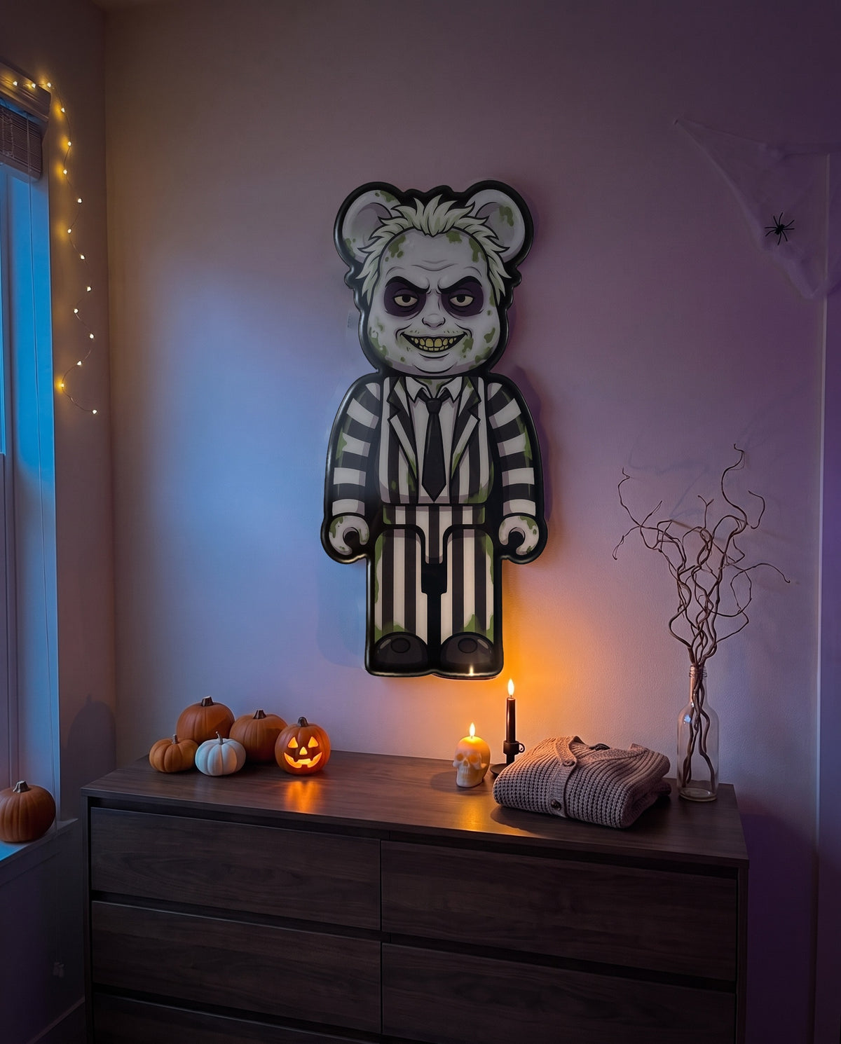 Beetlejuice Halloween Bear Wall Art hanging on the wall above a dresser in a Halloween-decorated room