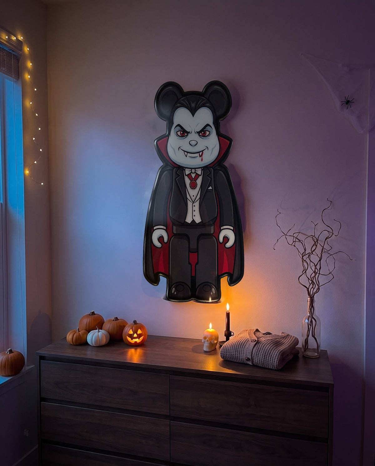 Dracula Halloween Bear Wall Art hanging on the wall above a dresser in a Halloween-decorated room